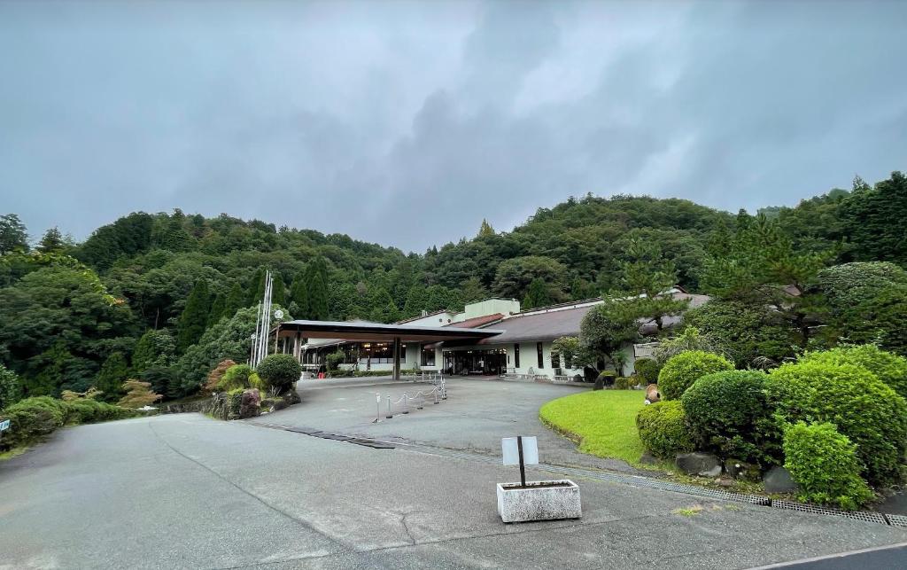 un bâtiment avec un parking en face d'une montagne dans l'établissement HOTEL GEN 猪名川店, à Yamashita