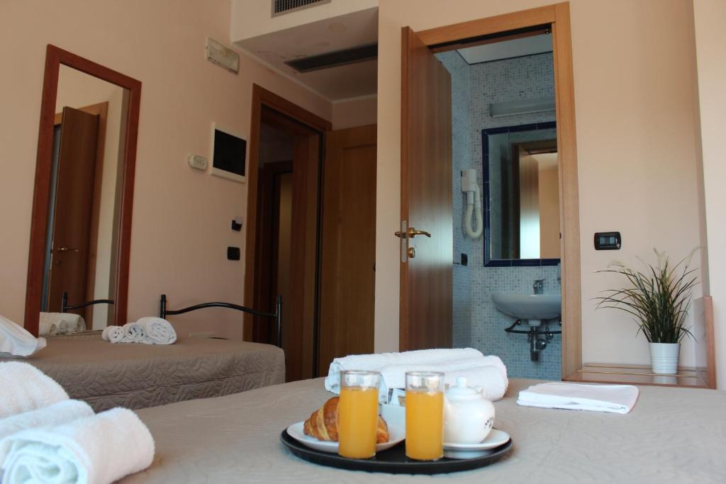 une chambre d'hôtel avec une table avec des verres de jus d'orange dans l'établissement Hotel Jole, à Cesenatico