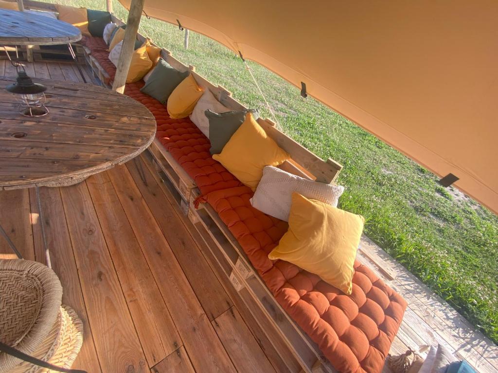 - un canapé avec des oreillers sur une terrasse avec une table dans l'établissement La Bêle & Toile, à Thiel-sur-Acolin