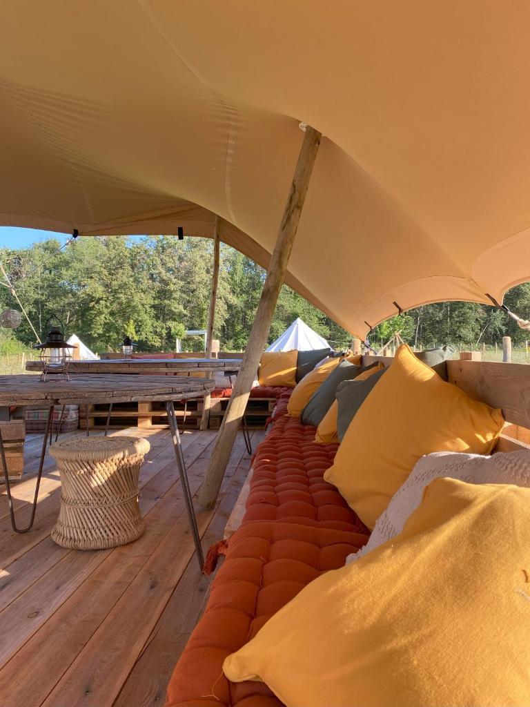 une grande tente avec des oreillers sur une terrasse en bois dans l'établissement La Bêle & Toile, à Thiel-sur-Acolin