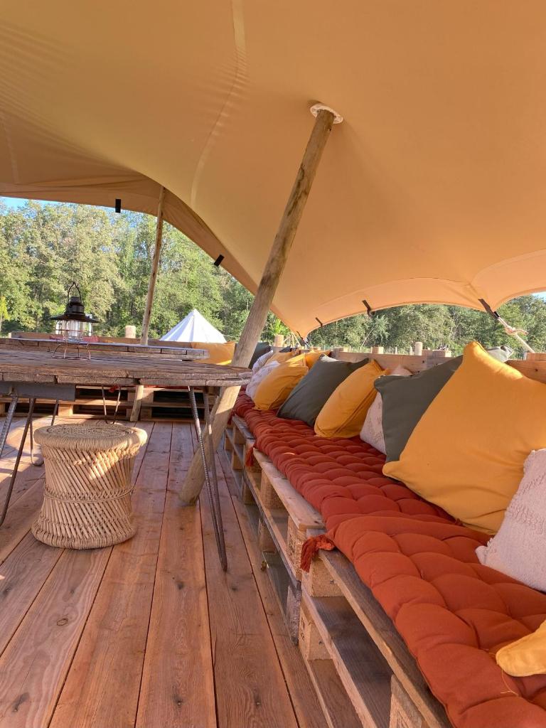 - une rangée d'oreillers sur une terrasse en bois dans une tente dans l'établissement La Bêle & Toile, à Thiel-sur-Acolin