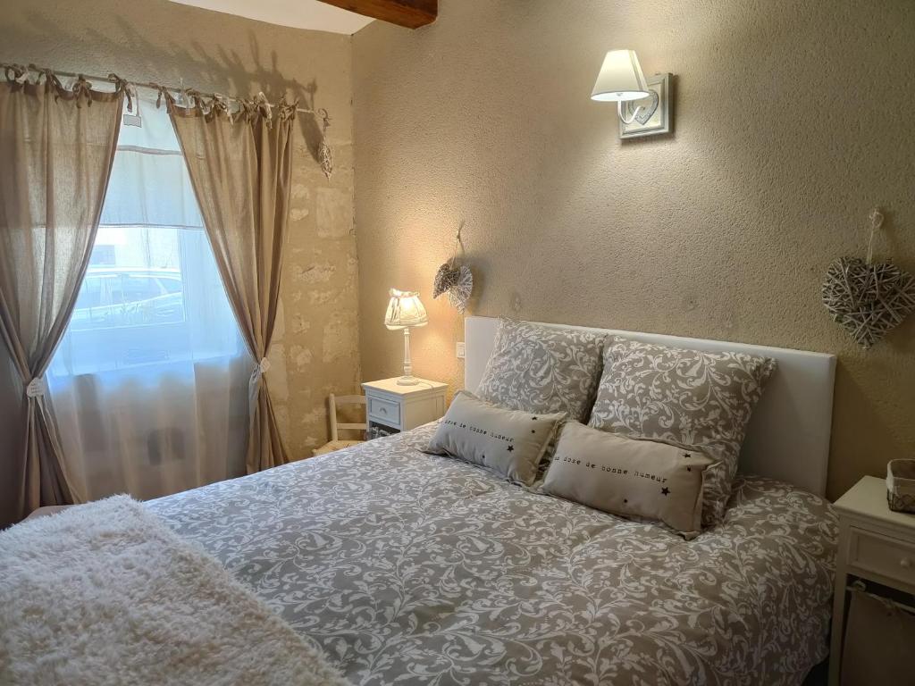 une chambre avec un lit blanc avec des oreillers et une fenêtre dans l'établissement Gîte Les Piraudières, à Noyant-de-Touraine