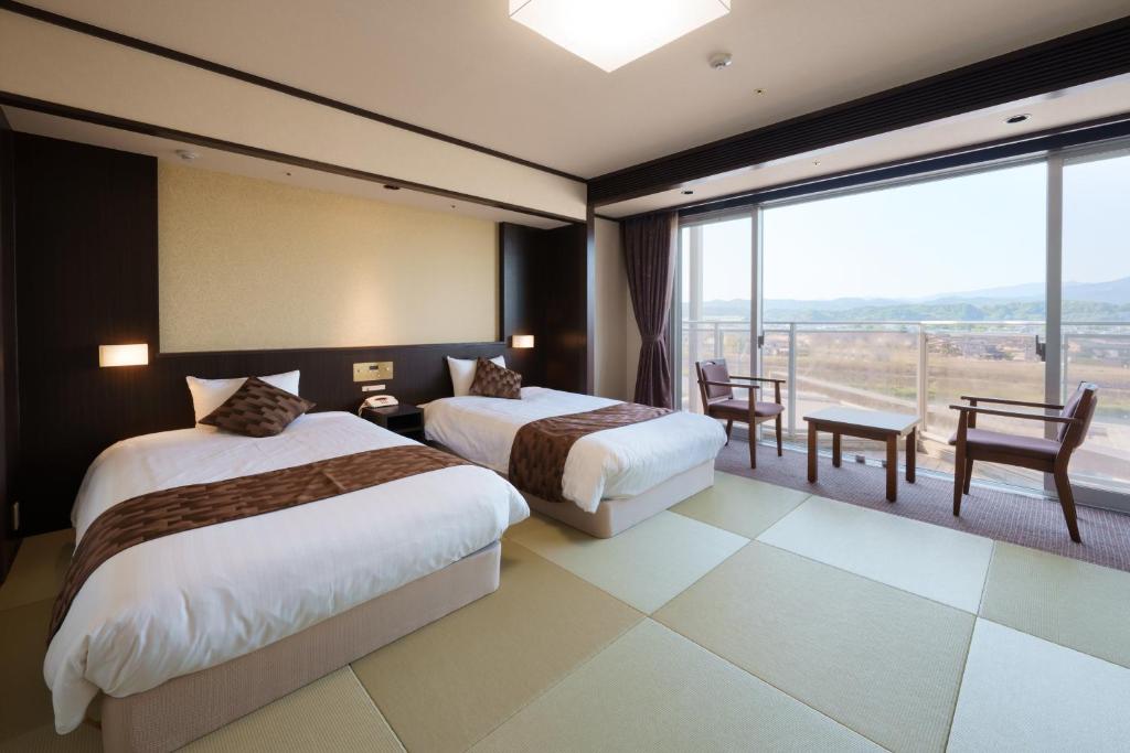 une chambre d'hôtel avec deux lits et un balcon dans l'établissement Hitaonsen Hananoki River Terrace, à Hita