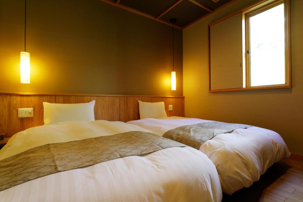 deux lits dans une chambre avec une fenêtre dans l'établissement Yukemuri no Yado Inazumi Onsen, à Yuzawa