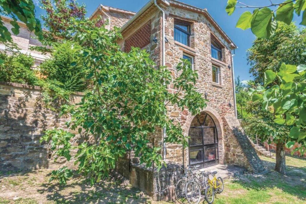 une vieille maison en pierre avec un arbre en face de celle-ci dans l'établissement Villa La Lucertola - Private Pool & AC In Umbrian Village, à Morra