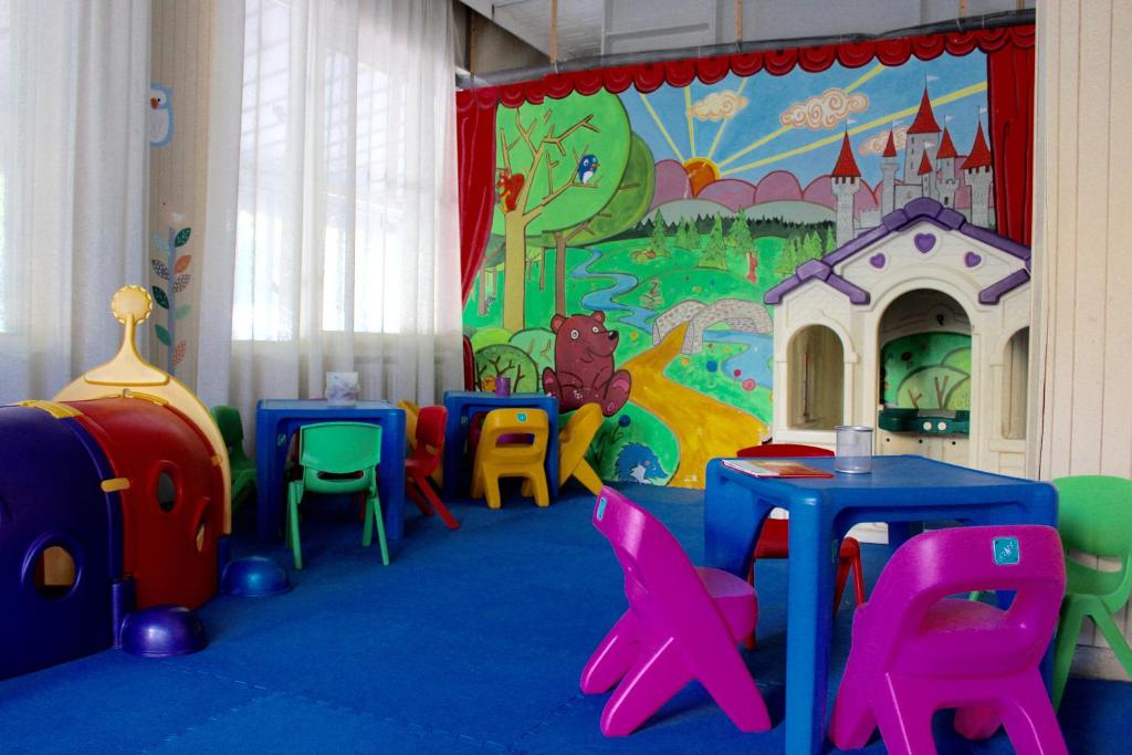 une salle de jeux pour enfants avec des tables et des chaises ainsi qu'une fresque murale représentant le château. dans l'établissement Jole Beach Hotel, à Cesenatico
