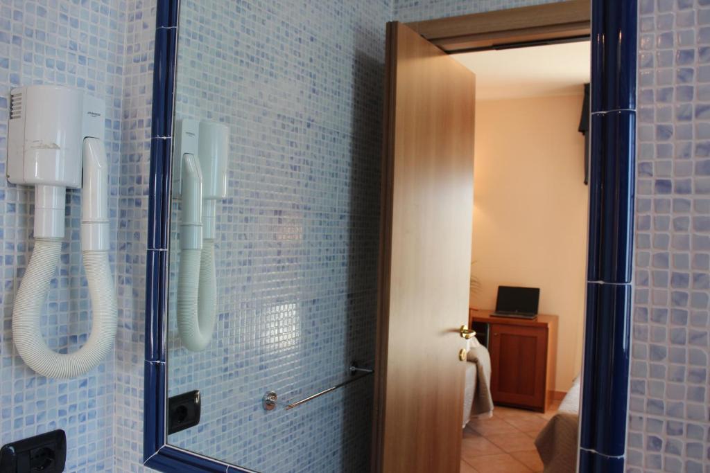 La salle de bains est pourvue d'un miroir et de carreaux bleus. dans l'établissement Jole Beach Hotel, à Cesenatico 4 autres photos