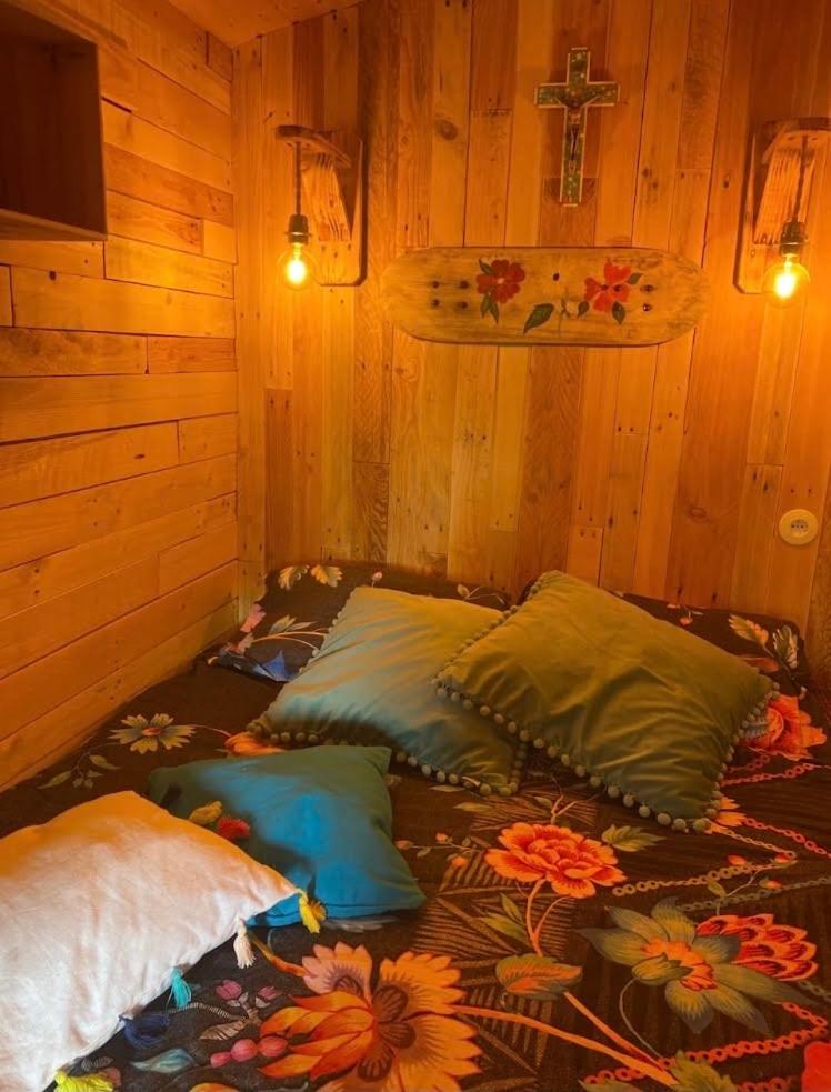 Cette chambre comprend 4 oreillers sur un lit avec une croix sur le mur. dans l'établissement Roulotte de Charme, à Bréconchaux