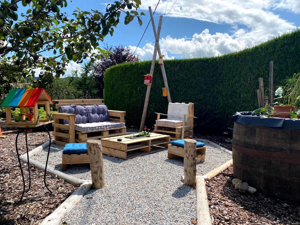 un jardin avec un banc, des chaises et une balançoire dans l'établissement Roulotte de Charme, à Bréconchaux