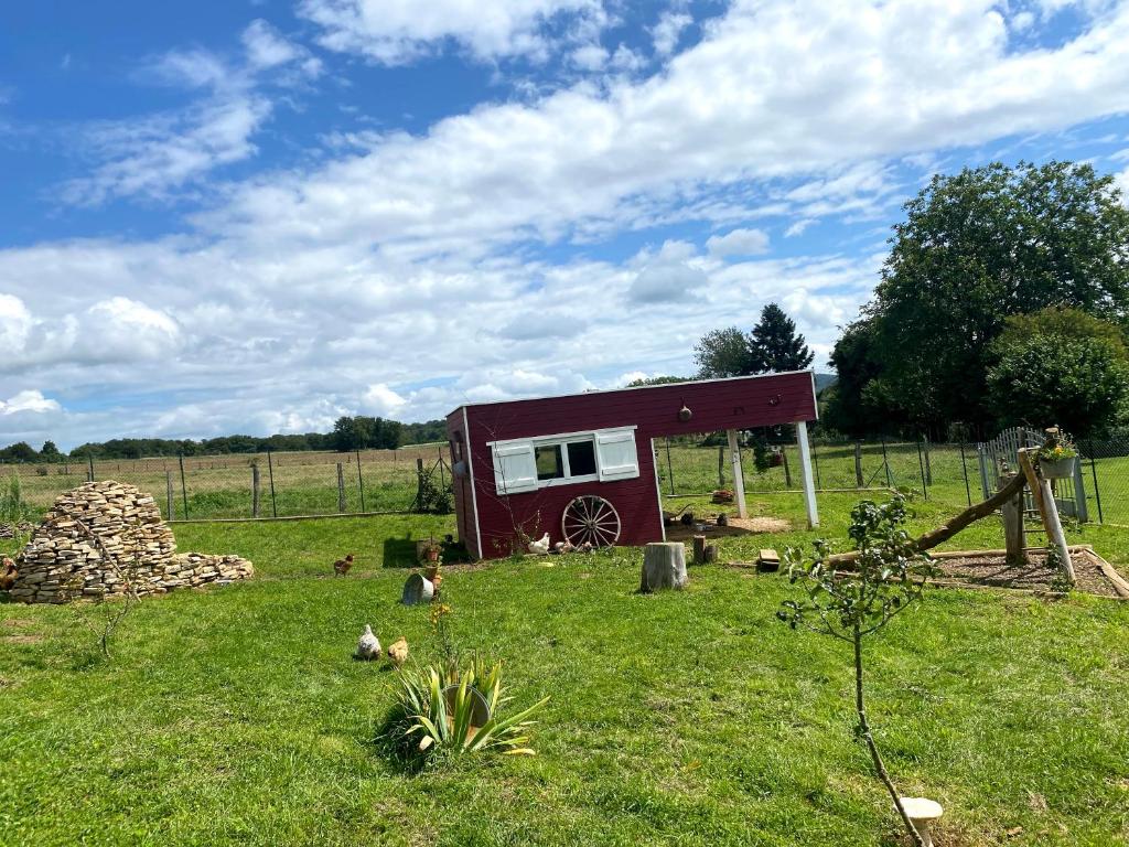 une petite étable rouge dans un champ avec des poulets dans l'herbe dans l'établissement Roulotte de Charme, à Bréconchaux 8 autres photos