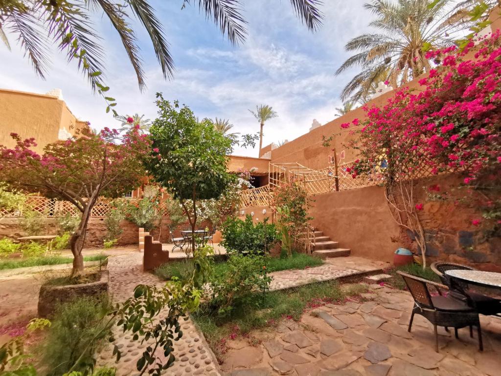 un jardin avec des fleurs roses et une table et des chaises dans l'établissement Riad Dar Zaouia, à Zagora