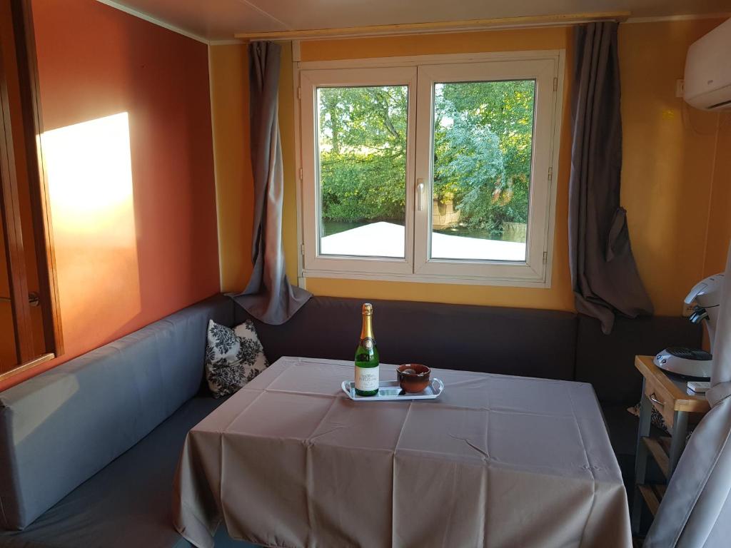 - une bouteille de champagne assise sur une table dans une chambre avec fenêtre dans l'établissement Cottage flottant Saint Jean de Losne option jacuzzi, à Saint-Jean-de-Losne