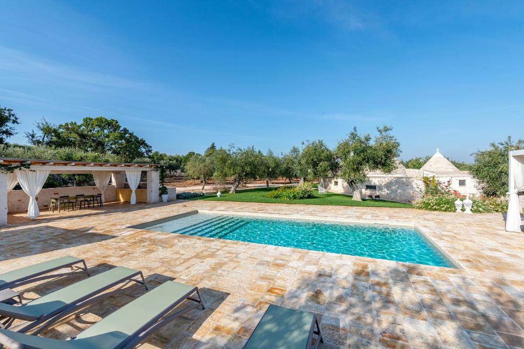 une image d'une piscine dans une cour avec des chaises dans l'établissement Trulli Vecchia Corte Monopoli, à Monopoli