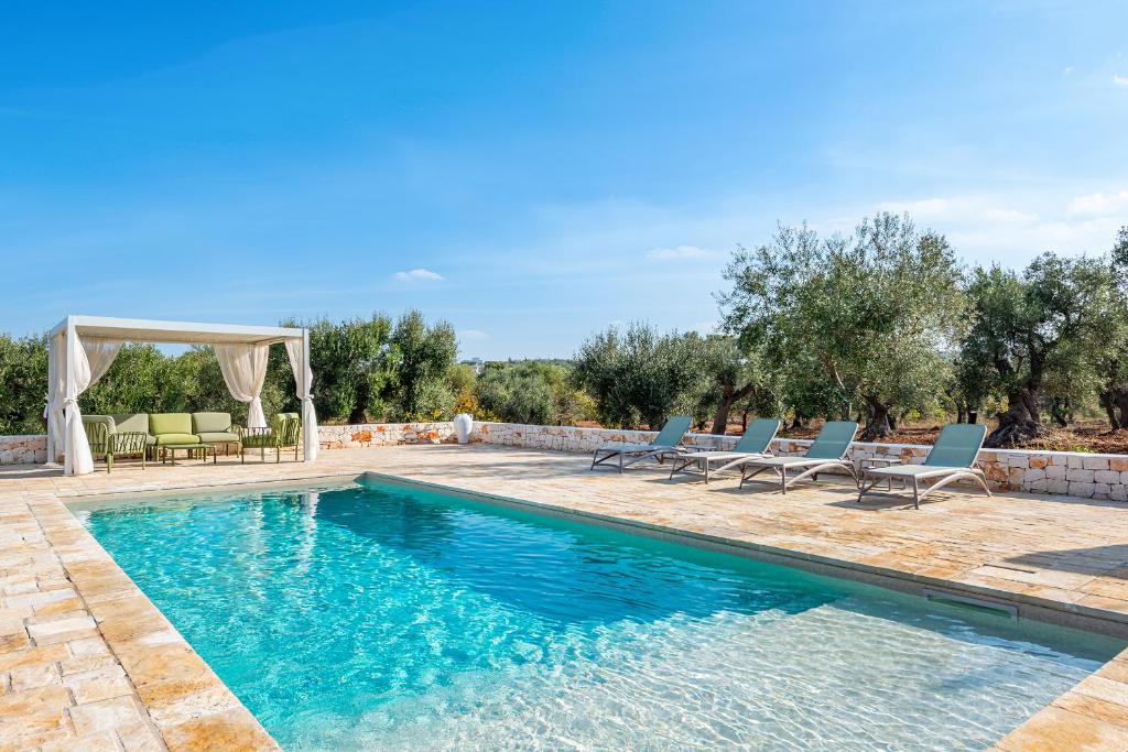 une piscine avec des chaises et un gazebo dans l'établissement Trulli Vecchia Corte Monopoli, à Monopoli