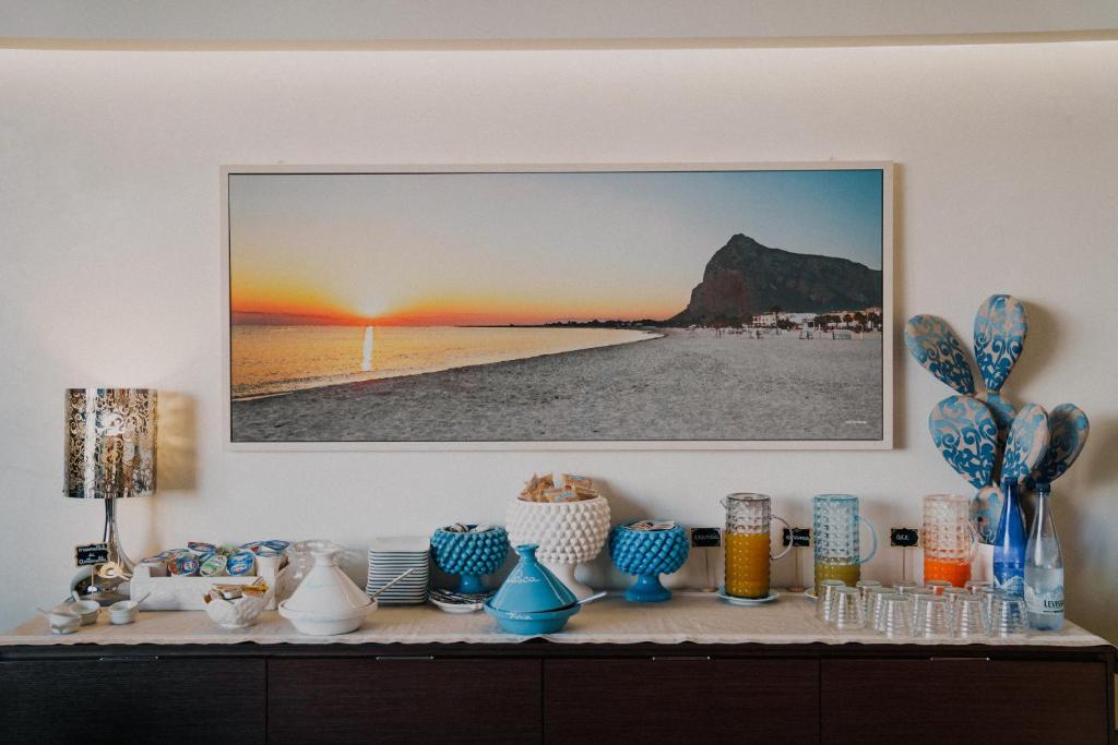 une table avec des vases bleus et un tableau sur un mur dans l'établissement Hotel Piccolo Mondo, à San Vito Lo Capo