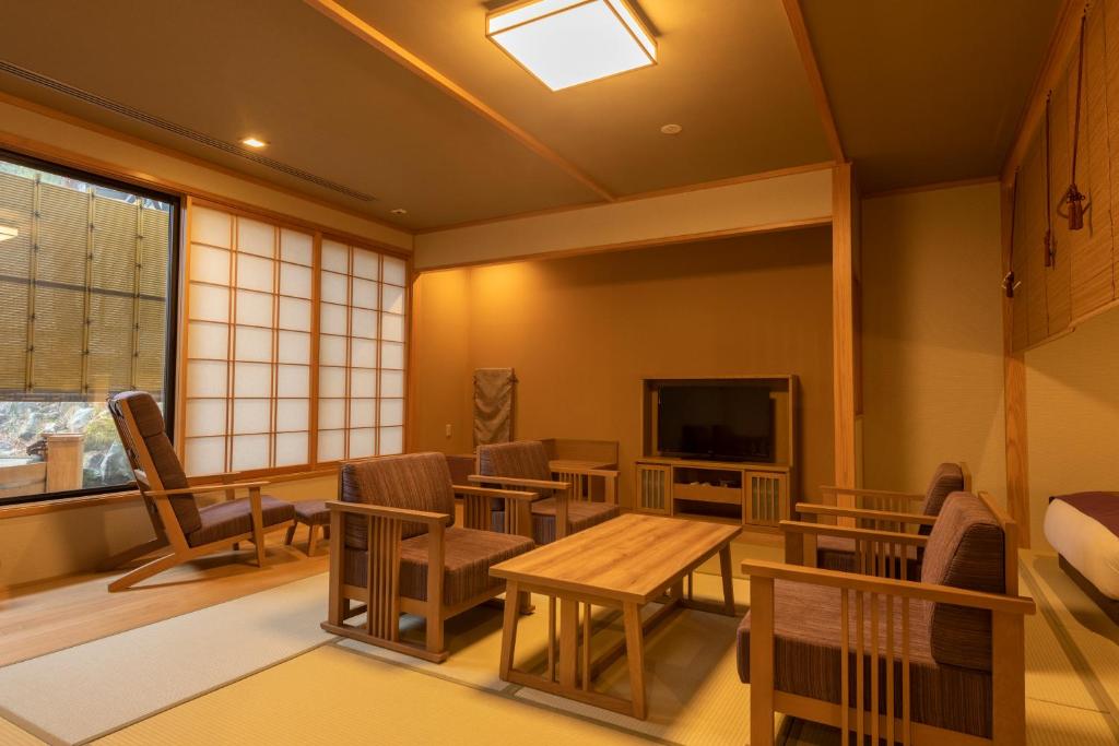 une chambre avec des chaises, une table et une télévision dans l'établissement Yukemuri no Yado Inazumi Onsen, à Yuzawa
