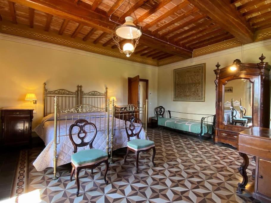 - une chambre avec un lit, deux chaises et un miroir dans l'établissement Tenuta Uzielli an elegant countryside villa, à Monteriggioni