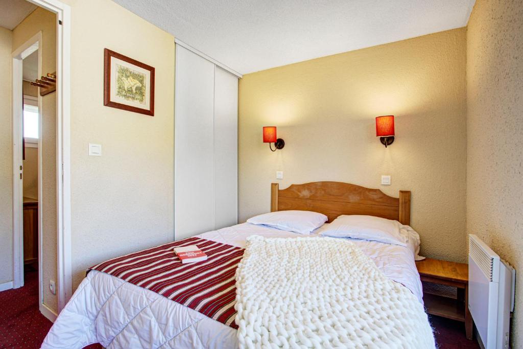 - une chambre dotée d'un lit avec une couverture rouge et blanche dans l'établissement Résidence Pierre & Vacances Pyrenees 2000 Le Séquoia, à Bolquère-Pyrénées 2000