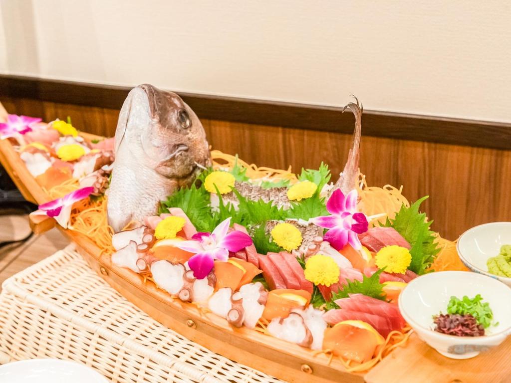 une assiette de nourriture avec un poisson et des fleurs dessus dans l'établissement LiVEMAX RESORT Kusatsu Onsen, à Kusatsu