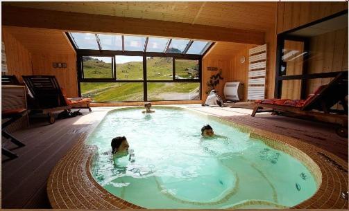 - 2 personnes dans une piscine dans une maison dans l'établissement Hôtel les skieurs, à Bellevaux
