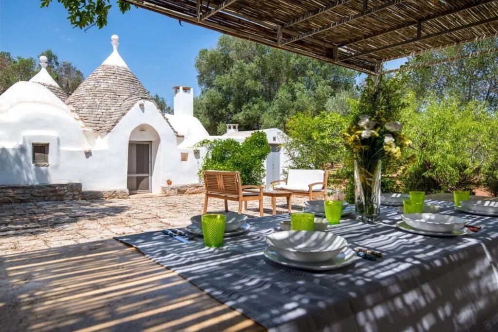 une table avec des assiettes et un vase de fleurs dans l'établissement Trullo Cristiana, à Latiano