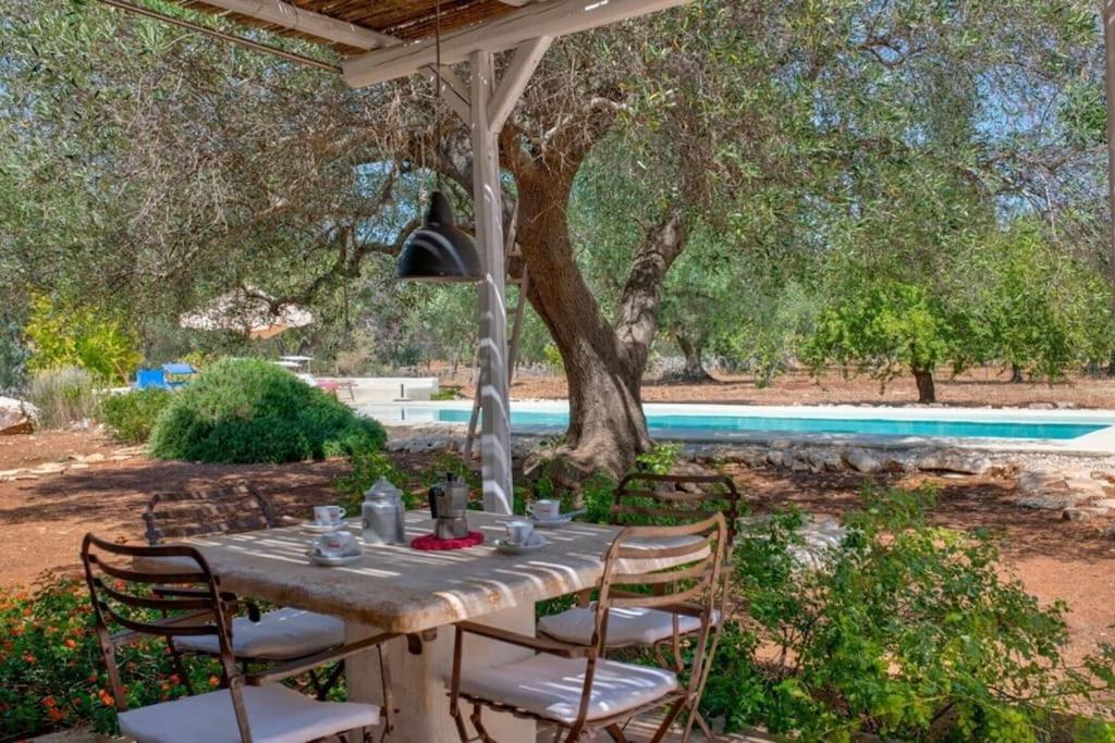 - une table et des chaises sous un parasol à côté de la piscine dans l'établissement Trullo Cristiana, à Latiano