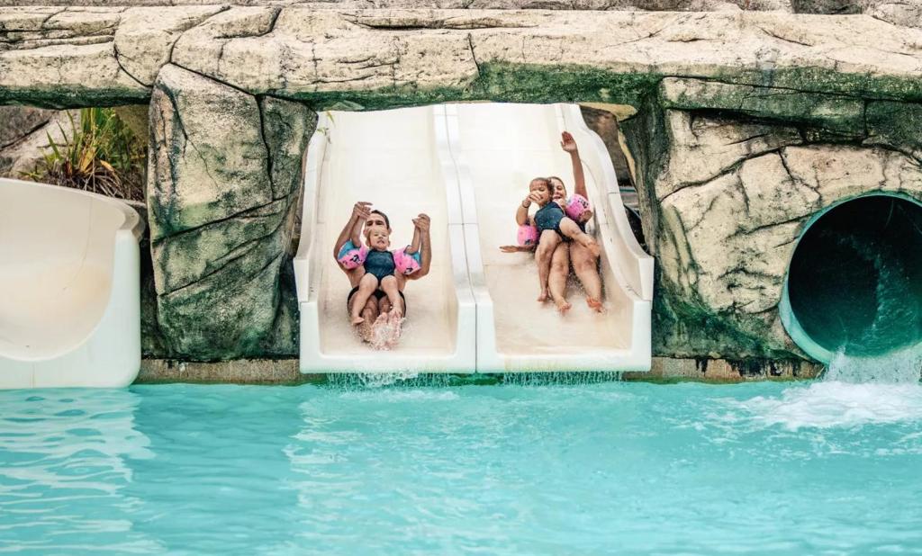 3 filles assises sur un toboggan dans un parc aquatique dans l'établissement Glamping Bretagne, à Quimper