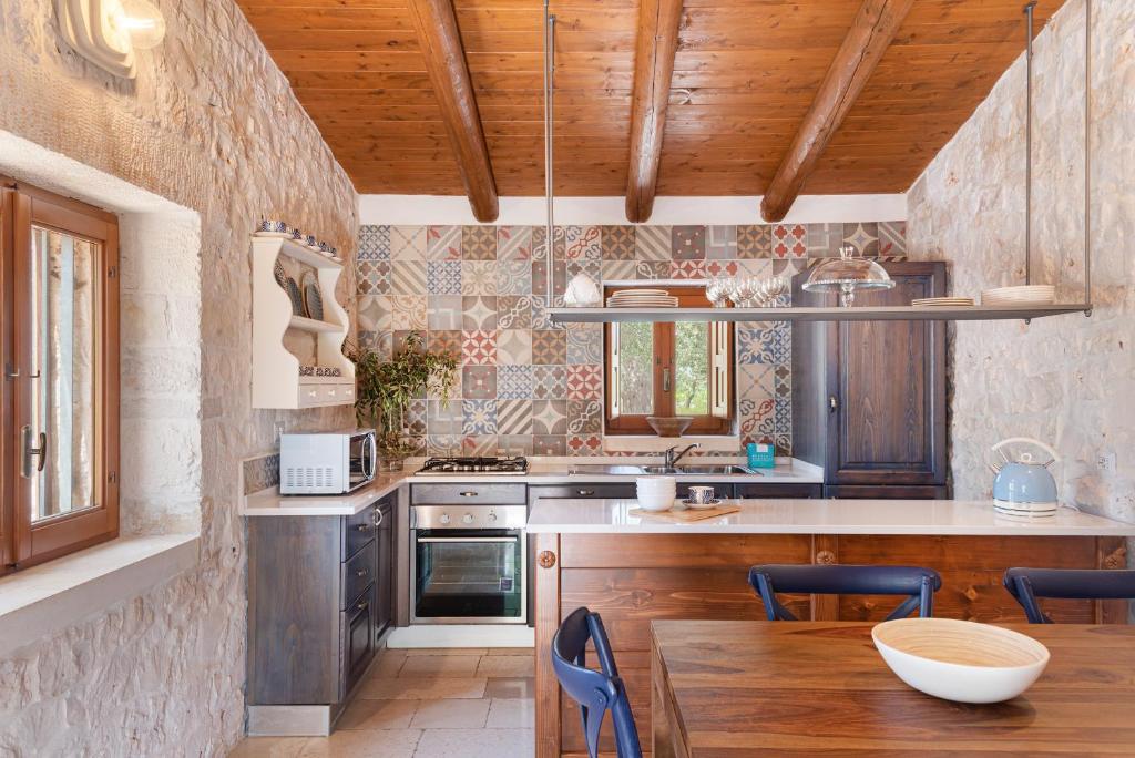 Il comprend une cuisine avec des plafonds en bois, une table et des chaises. dans l'établissement Trullo Fantastico, à Castellana Grotte