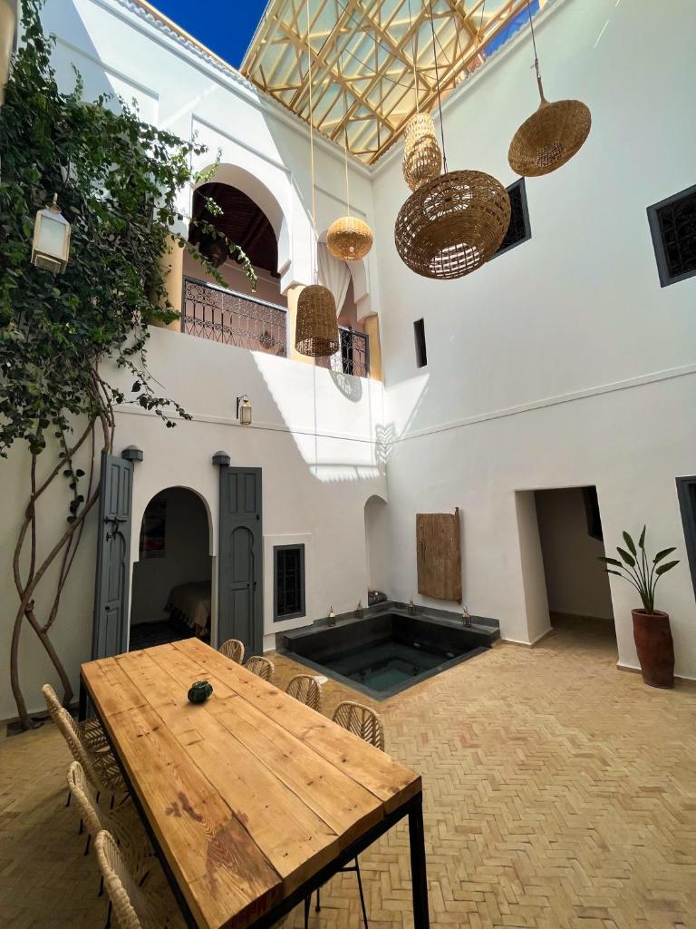 Cette grande chambre dispose d'une table et de chaises en bois. dans l'établissement Riad l'Echappée, en exclusivité, 5 chambres, à Marrakech