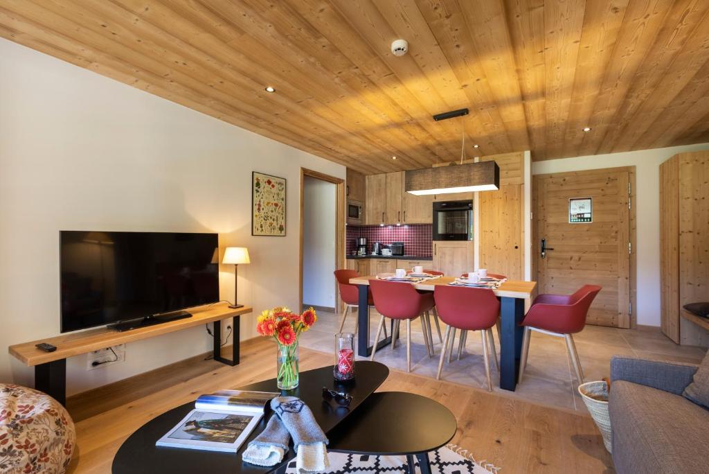 un salon avec un canapé et une table avec des chaises dans l'établissement Chalet Hôtelier LES EQUINOXES - VAL D'ISERE, à La Daille