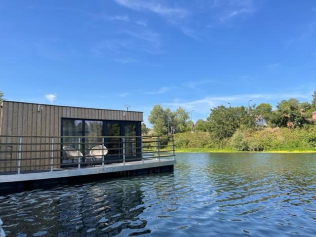 une maison sur un quai sur un plan d'eau dans l'établissement Gîte Seine & Nature Le Bâbord, à Bennecourt