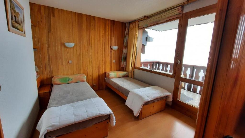 une petite chambre avec deux lits et une fenêtre dans l'établissement APPART ZIG-ZAG LES COCHES, à Les Coches