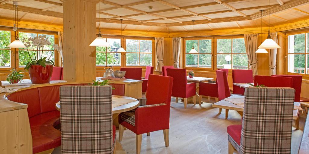 un restaurant avec des chaises rouges, des tables et des fenêtres dans l'établissement Hotel Weihrerhof, à Soprabolzano