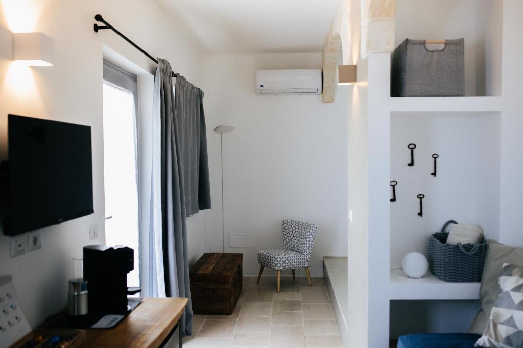 Cette petite chambre blanche dispose d'une télévision et d'une chaise. dans l'établissement Borgo Chiancarosa, à Putignano