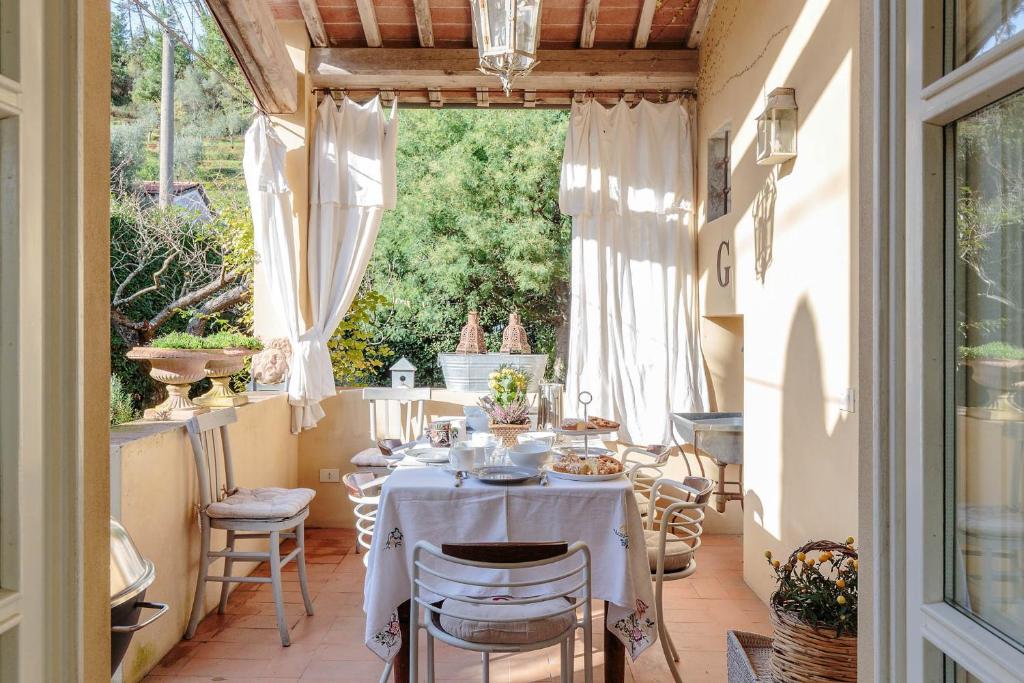 une salle à manger avec une table et des chaises sur un patio dans l'établissement Villa Label, when creativity meets style in endless romanticism, à Corsanico-Bargecchia