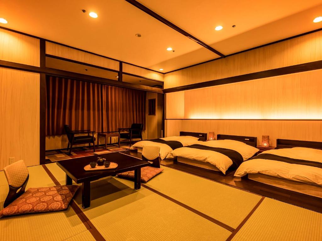 une chambre d'hôtel avec deux lits et une table dans l'établissement Ooedo Onsen Monogatari Premium Seiunkaku, à Awara 37 autres photos