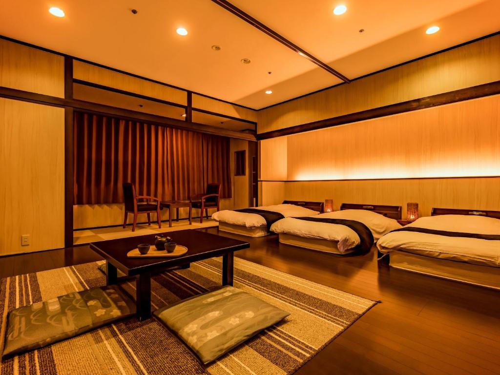 une chambre d'hôtel avec deux lits et une table dans l'établissement Ooedo Onsen Monogatari Premium Seiunkaku, à Awara