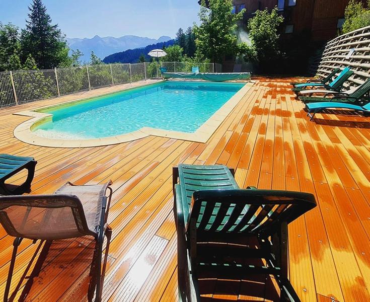 - une piscine sur une terrasse en bois avec des chaises dans l'établissement LES PETITS ETERLOUS Appartement T3 36m2 à Puy St Vincent 1800 Alpes du sud 6 personnes parking privé couvert, à Puy-Saint-Vincent 16 autres photos
