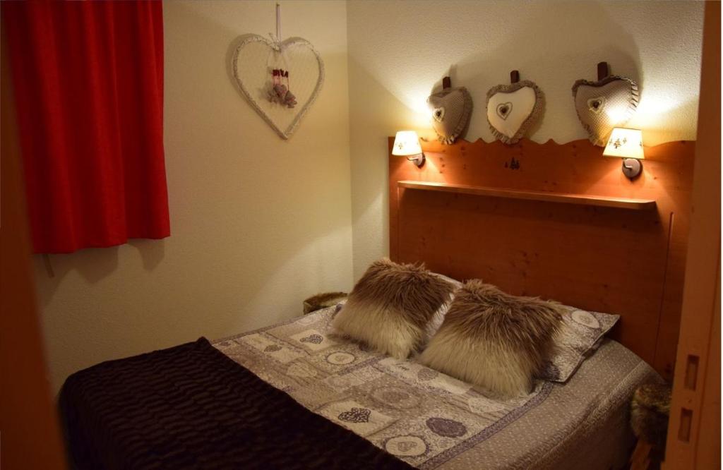 une chambre avec un lit avec deux oreillers dessus dans l'établissement LES PETITS ETERLOUS Appartement T3 36m2 à Puy St Vincent 1800 Alpes du sud 6 personnes parking privé couvert, à Puy-Saint-Vincent