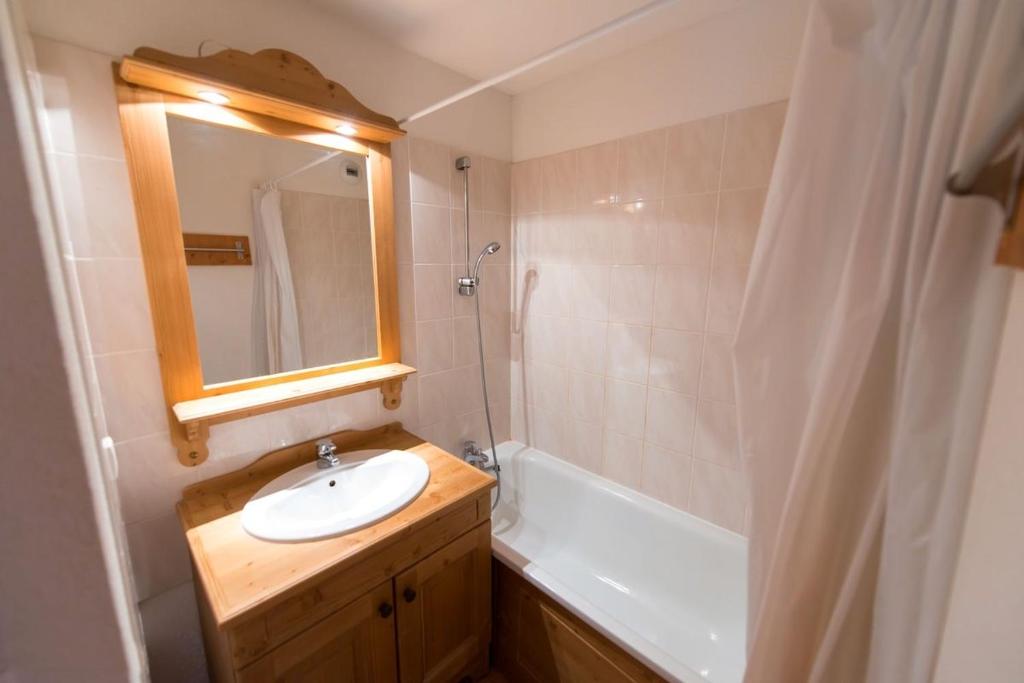 une salle de bain avec un lavabo, un miroir et une baignoire dans l'établissement LES PETITS ETERLOUS Appartement T3 36m2 à Puy St Vincent 1800 Alpes du sud 6 personnes parking privé couvert, à Puy-Saint-Vincent