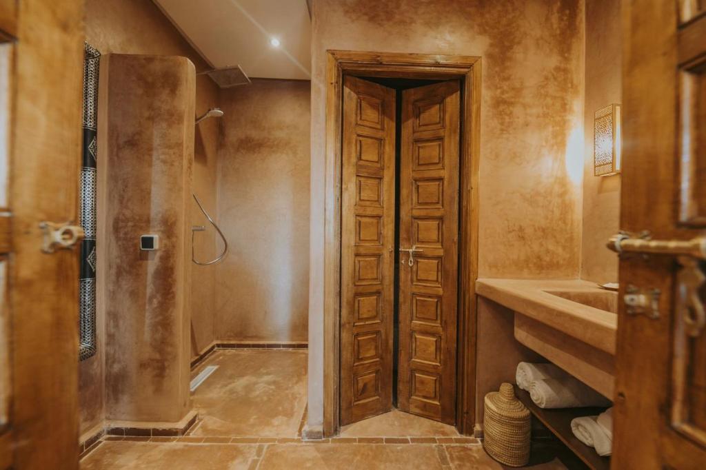 La salle de bains est pourvue d'une douche et d'une porte en bois. dans l'établissement Riad 64 Maison D'hôtes & Spa, à Marrakech 37 autres photos
