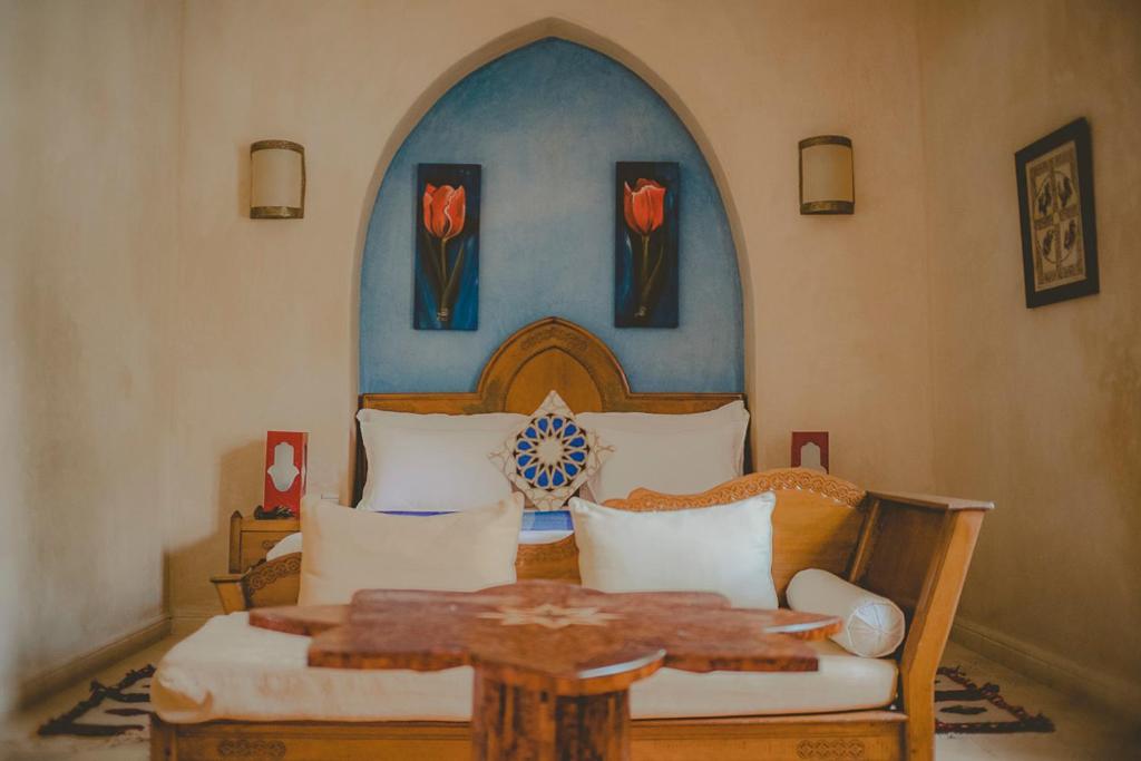 - une chambre avec un lit, une table et des fleurs dans l'établissement Palais Des Remparts, à Essaouira