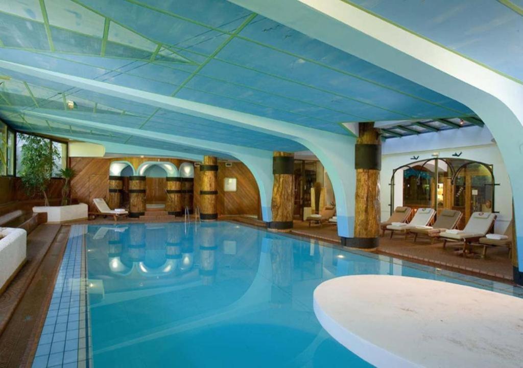une grande piscine dans un hôtel doté d'un plafond bleu dans l'établissement Résidence Le Domaine du Jardin Alpin - Courchevel 1850, à Courchevel