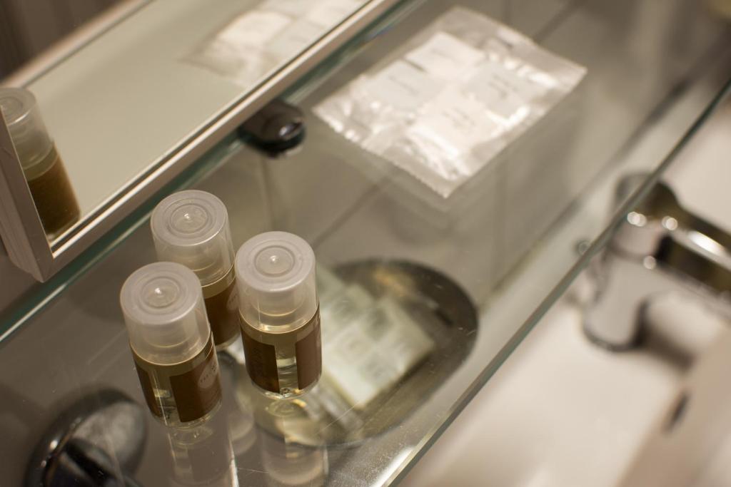 un comptoir en verre avec cinq bouteilles devant un miroir dans l'établissement Hotel La Perla Preziosa, à Grottammare