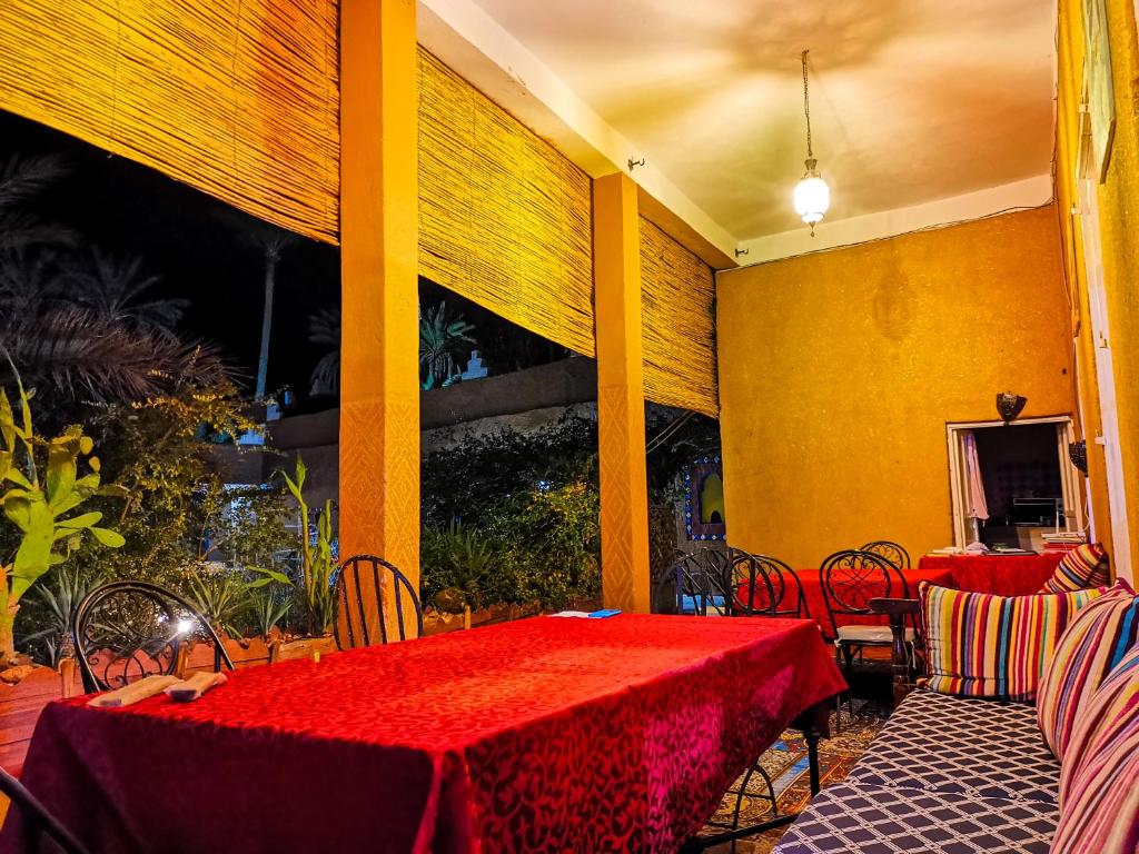 un restaurant avec deux tables et des chaises avec un tissu de table rouge dans l'établissement Riad Dar Zaouia, à Zagora