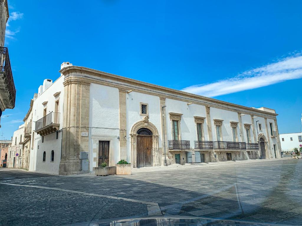 un grand bâtiment blanc au bord d'une rue dans l'établissement Palazzo Giustiniani L'Ambasciatore, à Sogliano Cavour