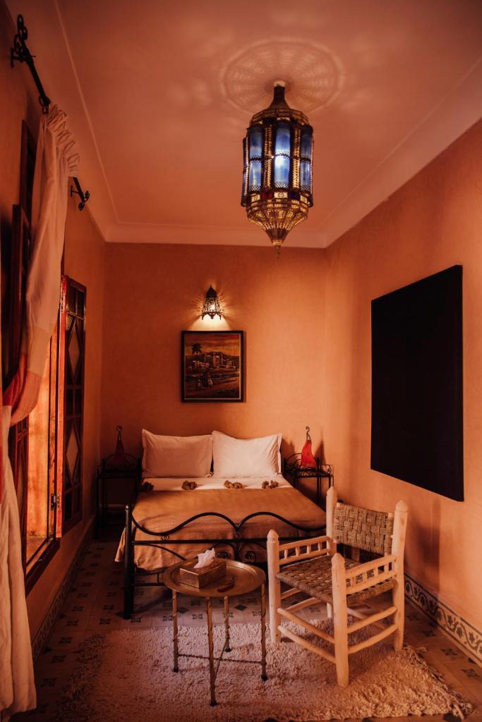 une chambre avec un lit et un lustre dans l'établissement Riad Bensaid, à Marrakech