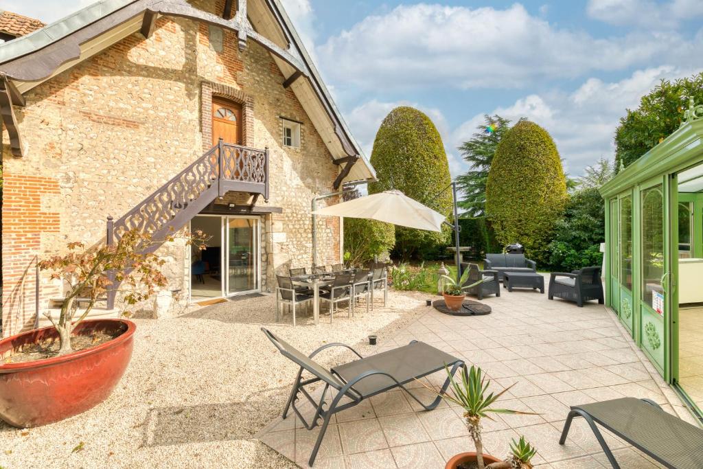 un patio avec des chaises et des tables et un bâtiment dans l'établissement Le Clos des Roches, à La Bouille