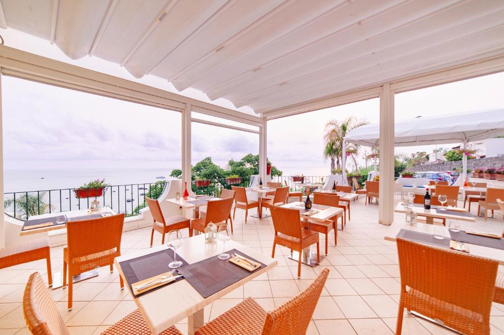 un restaurant avec des tables et des chaises et une vue sur l'océan dans l'établissement Hotel Capizzo, à Ischia
