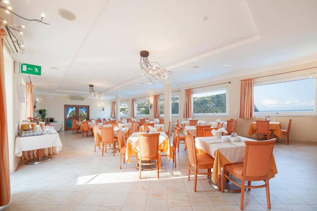 une salle à manger avec tables, chaises et fenêtres dans l'établissement Hotel Capizzo, à Ischia